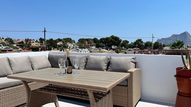 Een terras op het dak met rieten meubels, een fles champagne en glazen.