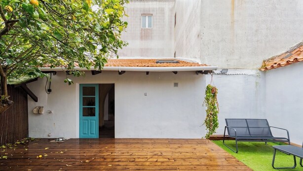 A wooden deck with a blue door leading to a white building, a hanging plant, and a black lounge chair. - Palmela Oasis Apartment II, By Home Match (Palmela)