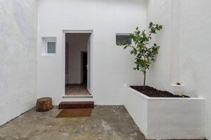 A narrow, white-walled corridor with a wooden door, a small window, and a potted plant. - Palmela Oasis Apartment II, By Home Match (Palmela)