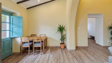 A dining area with a wooden table and chairs, a potted plant, and a blue door.