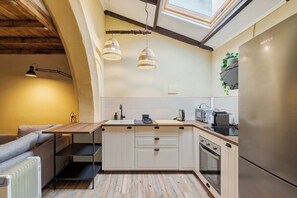 A compact kitchen with a built-in oven, a refrigerator, and a microwave. There is a wooden countertop and a small island with a sink. - Palmela Oasis Apartment II, By Home Match (Palmela)