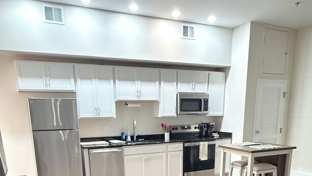 A modern kitchen with white cabinets, stainless steel appliances, and a patterned rug. - Newly Renovated Studio Apartment in Dowtown Roanoke (Roanoke)