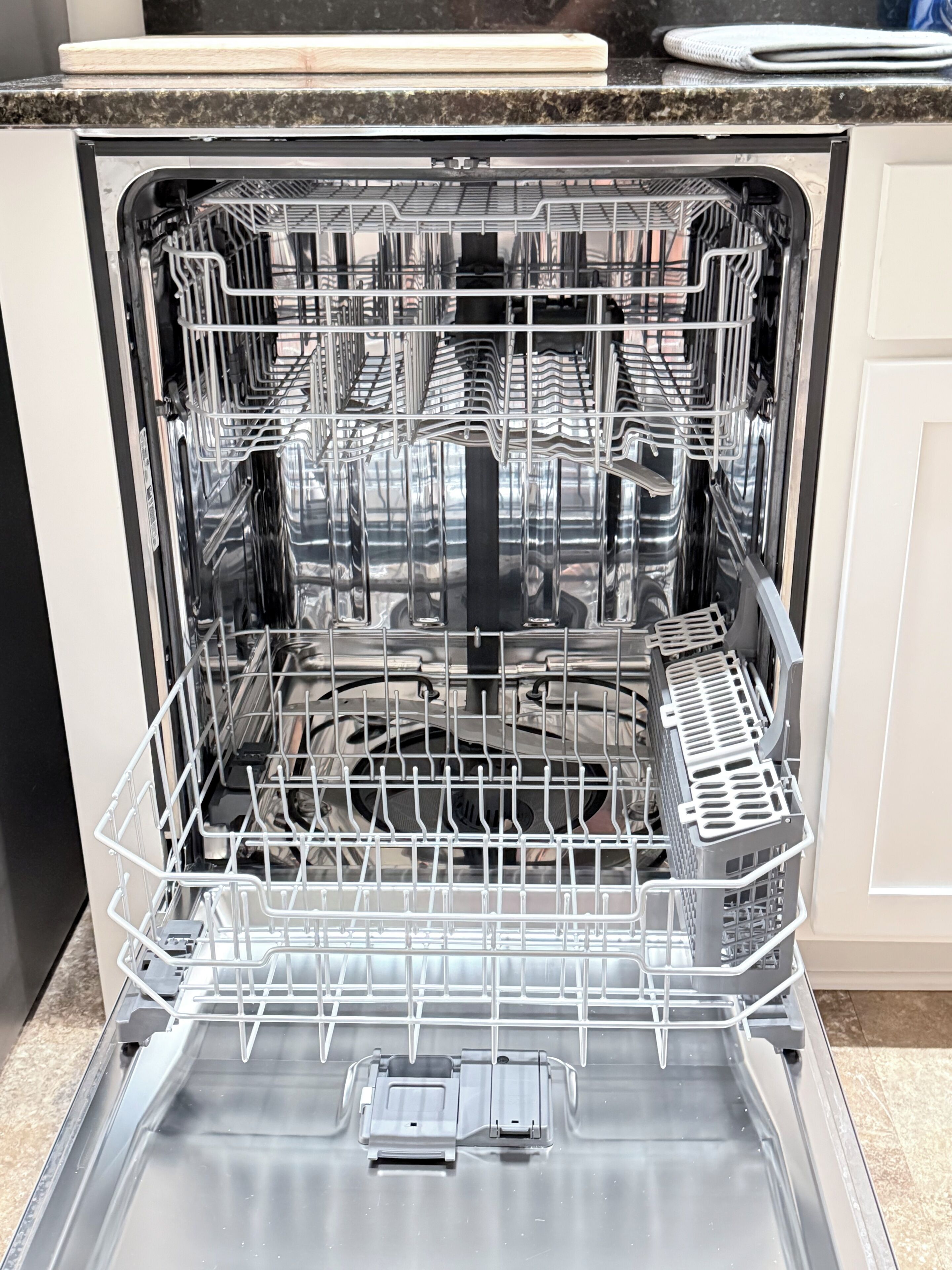 An open dishwasher with multiple racks and a control panel.