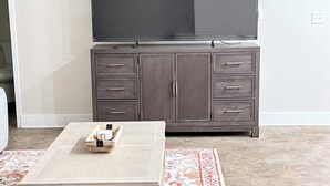 A living room with a flat-screen TV on a cabinet, a coffee table, and a patterned rug. - Newly Renovated Studio Apartment in Dowtown Roanoke (Roanoke)