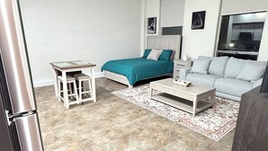 A modern living room with a bed, sofa, coffee table, and a small table with chairs. - Newly Renovated Studio Apartment in Dowtown Roanoke (Roanoke)