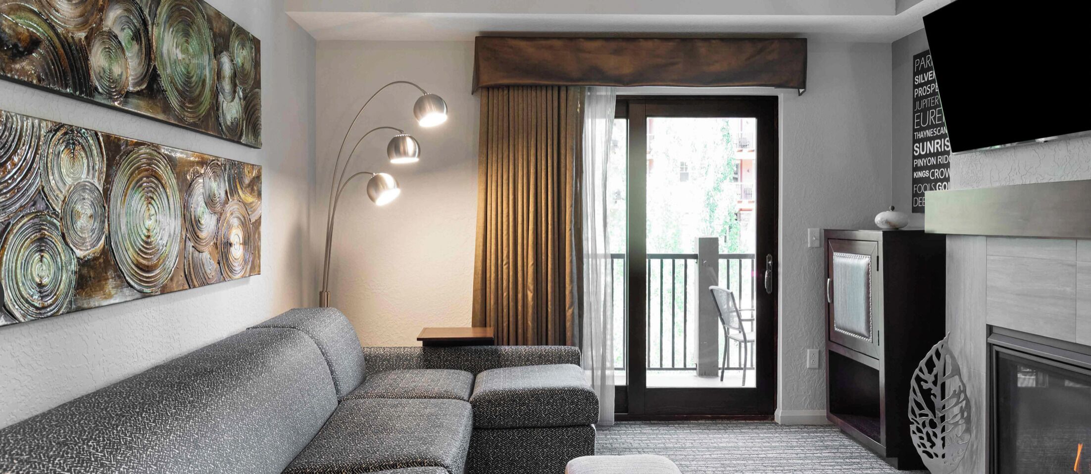 A modern living room with a sofa, a floor lamp, a fireplace, and a balcony with a chair.