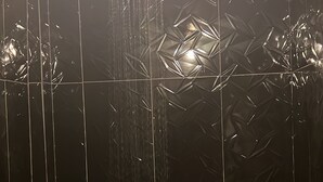 A shower with a modern design, featuring a geometric pattern on the walls and a visible water flow.