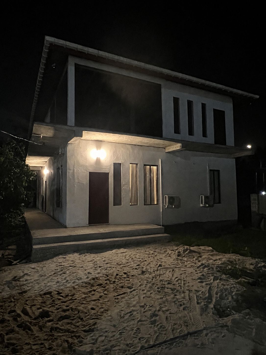 Ett modernt hus i två våningar med en väl upplyst entré och ett tydligt avgränsat utomhusområde.