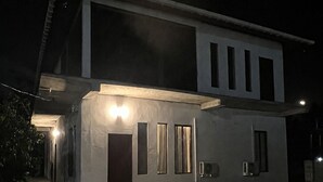 A modern two-story house with a well-lit entrance and a visible outdoor area.