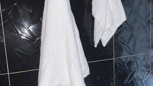 Two white towels hanging on a tiled wall.