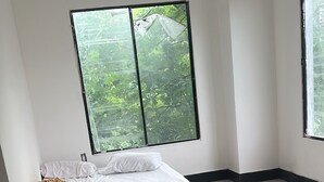 A room with a bed, large windows, and a tiled floor.
