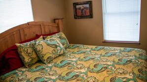 A bed with a patterned bedspread, a wooden headboard, and a red pillow. - Riverfront Cabins  and  Vacation Homes (Rio Frio)