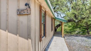 A building with a sign reading 'River Bluff,' a covered porch, and a gravel ground. - Riverfront Cabins  and  Vacation Homes (Rio Frio)