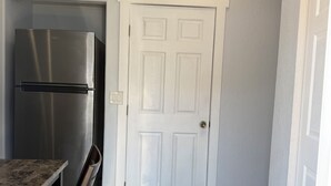 A kitchen with a stainless steel refrigerator, a white door, and a dining area with a bench. - Private 1BR Suite, Free Parking, Near Downtown & Airport (Tampa)