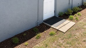A building with a white door, a small porch, and a black mat at the entrance. - Private 1BR Suite, Free Parking, Near Downtown & Airport (Tampa)