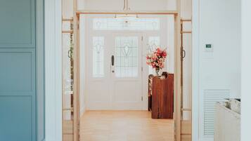 Un couloir avec une porte en bois, un petit bureau en bois orné d’un vase de fleurs et un radiateur sur le côté droit.