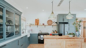 Una cocina con armarios azul claro, una isla de madera, una estufa y lámparas colgantes.