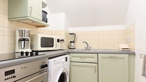 Uma cozinha equipada com cafeteira, micro-ondas, liquidificador e máquina de lavar.