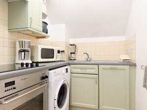 Eine Küche mit Kaffeemaschine, Mikrowelle, Mixer und Waschmaschine.