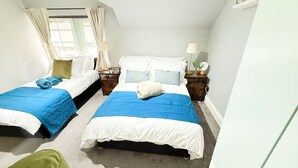 Quarto com duas camas, cada uma com colcha azul e branca, e uma cadeira verde.