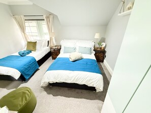 Ein Schlafzimmer mit zwei Betten, jeweils mit einer blauen und weißen Bettdecke, und einem grünen Sessel.