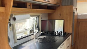 Une petite cuisine équipée avec une cuisinière, un évier et des placards en bois.