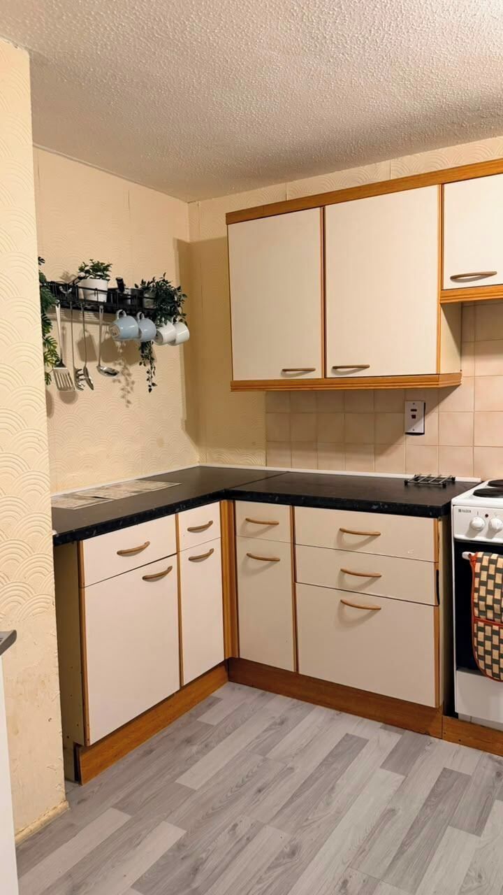A kitchen with white cabinets, a black countertop, and a stove.