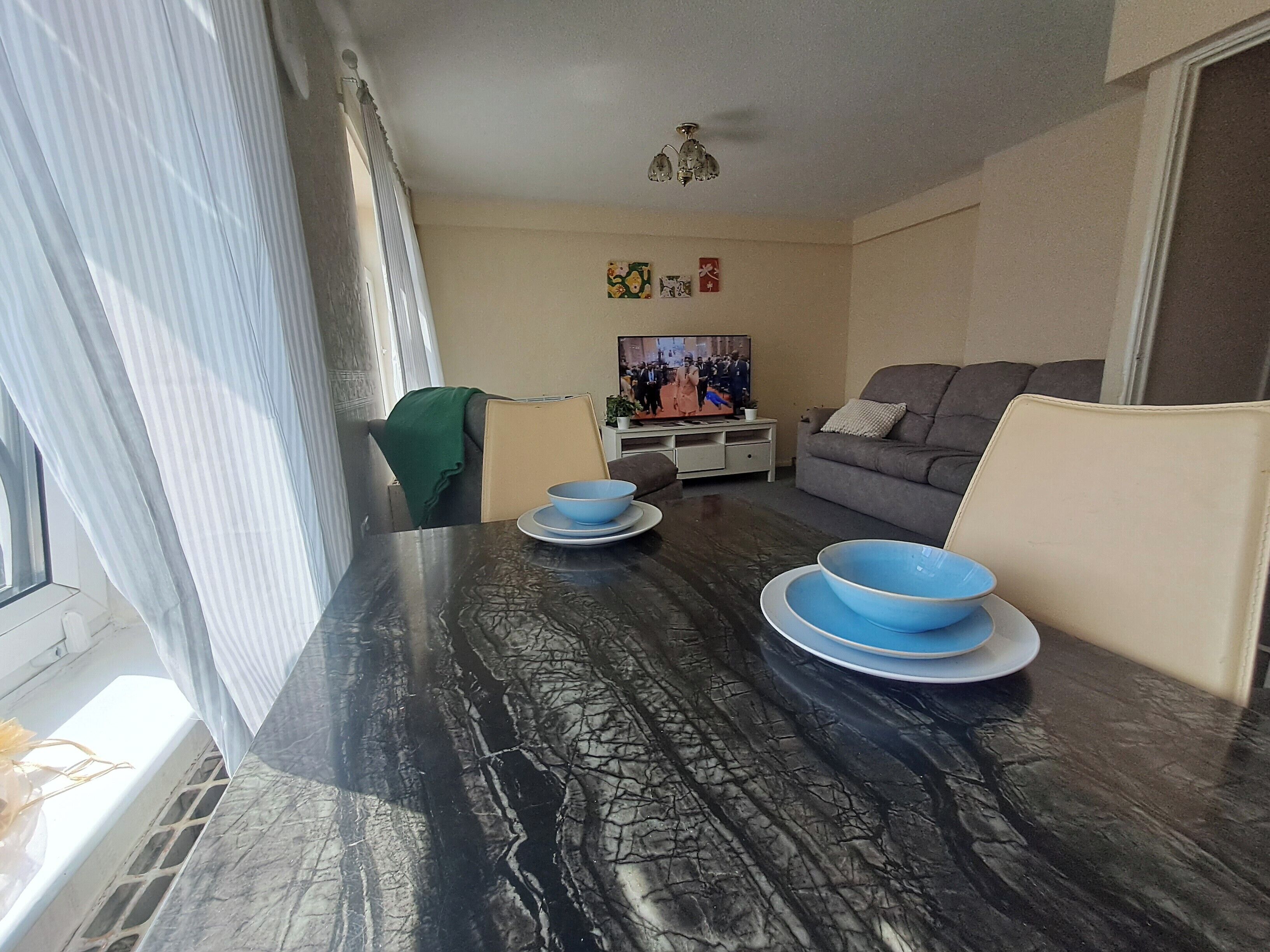 A living room with a dining table, a sofa, and a television.