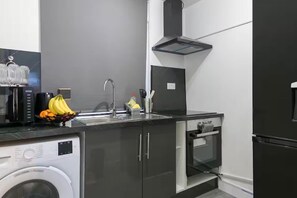 Una cocina moderna con lavadora, pileta y horno integrado.