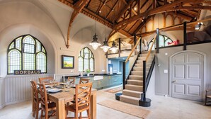 A spacious dining area with a high ceiling, wooden beams, and a staircase leading to an upper level. - Grade C Church in Cannich, Sleeps 2 w/ Parking (Beauly)