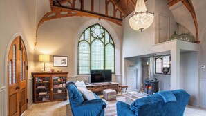 A cozy living room with a fireplace, a television, and blue sofas. - Grade C Church in Cannich, Sleeps 2 w/ Parking (Beauly)