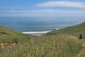 A coastal landscape with a grassy path leading to the sea, a person standing on the path, and a clear sky. - 3 Bedroom Cayton Bay Home Sleeps 8 - Pool (Scarborough)