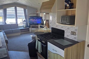 Ein kompakter Wohnbereich mit Küche, einer Sitzecke und einem Fernseher.