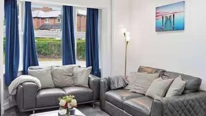 A living room with two grey sofas, a coffee table, and a vase with flowers. - Nottingham Home 4 Bedrooms sleeps 7 city hospital (Nottingham)
