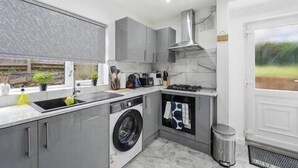A modern kitchen with a built-in washing machine, a sink, and a stove. - Nottingham Home 4 Bedrooms sleeps 7 city hospital (Nottingham)