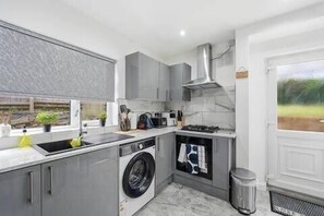 A modern kitchen with a built-in washing machine, a sink, and a stove. - Nottingham Home 4 Bedrooms sleeps 7 city hospital (Nottingham)