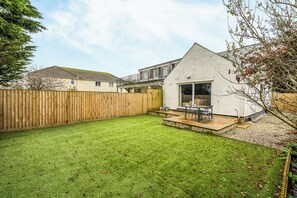 A residential property with a fenced backyard, a patio with outdoor seating, and a house with a sloped roof. - 2 Bed Apartment Sleeps 4 - Pets Welcome (St. Ives)