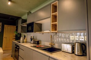 Eine moderne Küche mit integriertem Mikrowellenherd, Toaster und Wasserkocher, sowie einer Spüle und Schränken.
