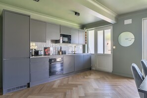 Une cuisine moderne avec des meubles de couleur grise, un four Bosch et une fenêtre à vitrage dépoli.