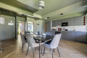 A modern kitchen with grey cabinets, a dining table set for four, and a visible microwave. - 2 Bedroom Apartment Sleeps 3 - Garden - Pets (St. Ives)