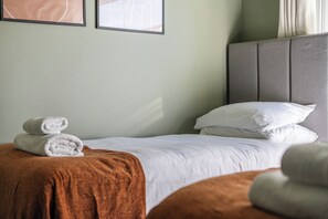 A hotel room with a bed, pillows, a blanket, and two rolled towels. - 2 Bedroom Apartment Sleeps 3 - Garden - Pets (St. Ives)