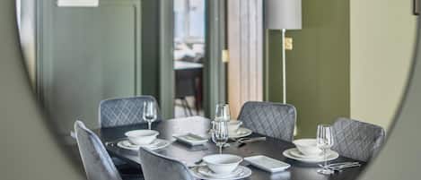 A dining area with a round table set for four, equipped with white plates, bowls, and cutlery.