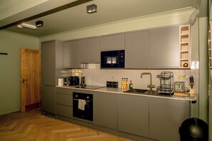Eine kleine Küche mit grauen Schränken, einer Bosch-Mikrowelle, einer Kaffeemaschine und einem Toaster.