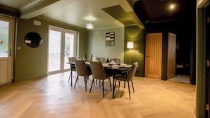 A dining area with a table set for four, a large window, and a door leading to another room. - 2 Bedroom Apartment Sleeps 3 - Garden - Pets (St. Ives)