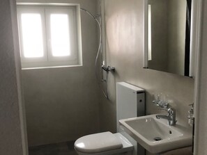 A small bathroom with a toilet, sink, and shower. - Abendstern, (Grächen), by Interhome (Grächen)