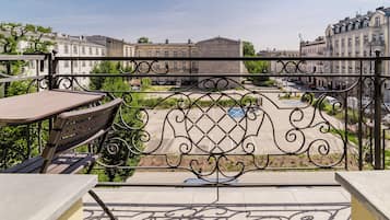 A balcony with a table and chairs, overlooking a cityscape with historic buildings and a clear sky.