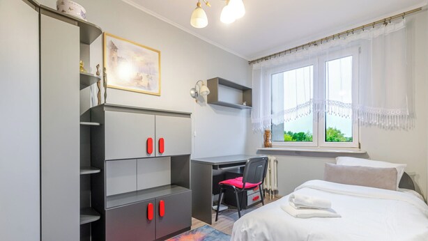 Ein Schlafzimmer mit einem Bett, einem Schreibtisch, einem Stuhl, einem Kleiderschrank und einem Fenster mit Blick.