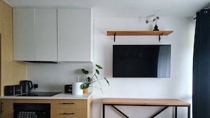 Une cuisine moderne équipée d’un four encastré, d’une machine à café et d’une plante posée sur le plan de travail.