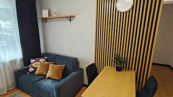 A living room with a blue sofa, a wooden table, and a clock on the wall.