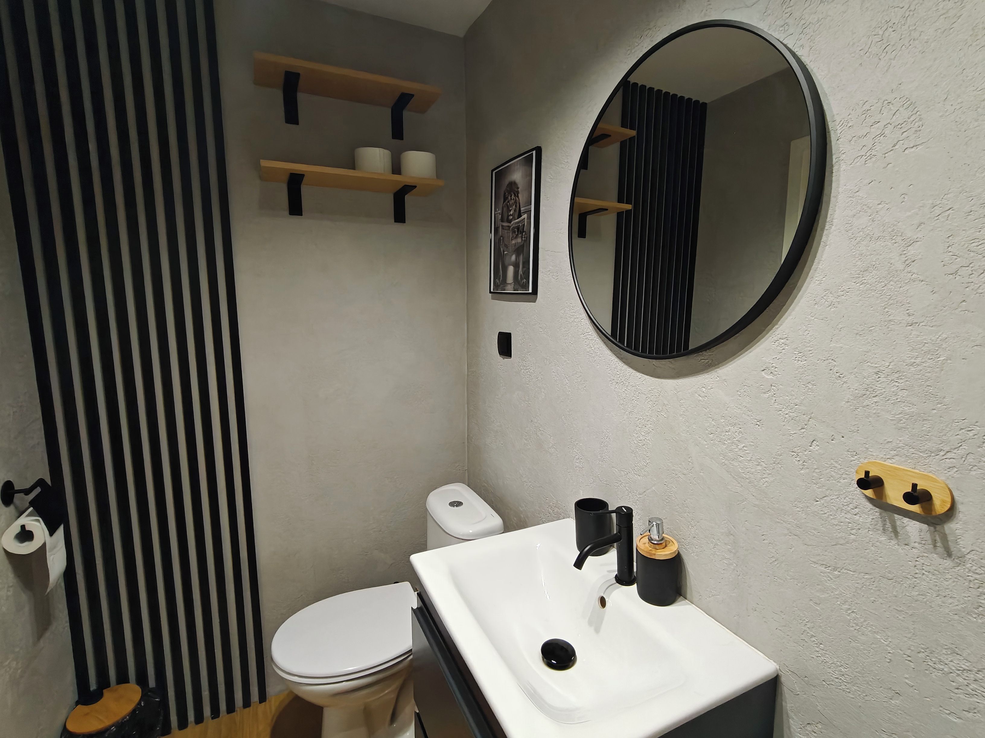 A bathroom with a toilet, sink, mirror, and towel rack.